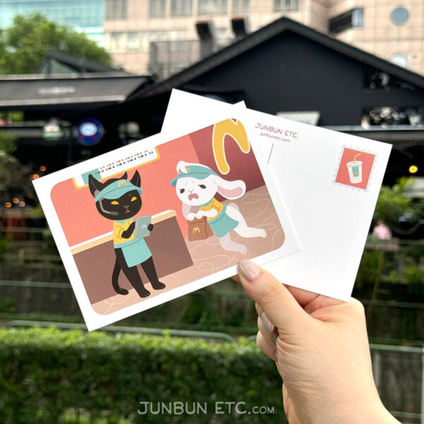 The graphic shows the MewBunny's postcard image depicting JunBun - the white rabbit mascot - and MaxCat - the black cat mascot - as fast food/diner/burger joint minimum wage workers, complete in MewBunny's uniforms and visors. MaxCat is reviewing orders on a tablet, and JunBun is falling over in dismay with a brown paper bag in paw.